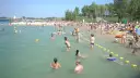 Tłum ludzi na plaży i w wodzie, idealne miejsce na wakacje z bonem turystycznym.