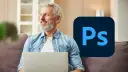 Uśmiechnięty mężczyzna z laptopem i logo Photoshop.