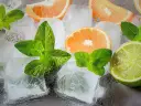 Jak zrobić krystaliczny lód w domu? Kostki lodu, plasterki pomarańczy, limonki i listki mięty tworzą orzeźwiającą kompozycję.