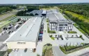 Nowoczesny kompleks produkcyjny Voster producent drzwi, z drogą szybkiego ruchu w tle.