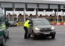 Policjant w kamizelce odblaskowej rozmawia z kierowcą przy bramkach. Czy autostrada A4 jest płatna? Tak, w tym miejscu pobierane są opłaty.
