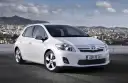 Biała Toyota Auris hybryda na tle miasta. Czy warto zainwestować w ten model?