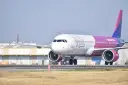 Samolot Wizzair z różowym ogonem na płycie lotniska.