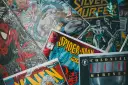 Stos komiksów z postaciami takimi jak Spider-Man, Batman i Silver Surfer. Czy komiks to książka? To zależy od tego, jak na to spojrzeć!