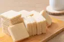 Chrupiące wafle z mlekiem w proszku i galaretką, ułożone na drewnianej desce. Idealne na deser.