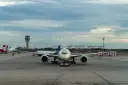 Samolot na płycie lotniska z wieżą kontroli lotów w tle.