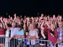 Tłum ludzi na koncercie, wszyscy z podniesionymi rękami, cieszą się muzyką. Widać uśmiechnięte twarze, a niektórzy nagrywają telefonami. To z pewnością niezapomniane **baciary utwory**!