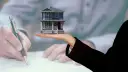 Model domu na dłoni, podczas gdy ktoś podpisuje dokumenty. Kluczowe pytanie: do kiedy rozliczenie za wynajem mieszkania?
