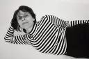 Katarzyna Krzanowska w czarno-białym swetrze w paski, leżąca na boku, z ręką pod głową.