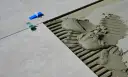 Płytki ceramiczne układane na kleju, widoczne kliny dystansowe i precyzyjnie określona szerokość fugi.