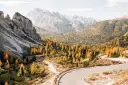 Malownicza droga w Dolomitach, otoczona jesiennymi drzewami, idealne miejsce na camping.