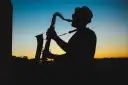 Sylwetka muzyka w kapeluszu grającego na saksofonie o zachodzie słońca. Prawdziwy mistrz, jeden z najlepszych bluesmanów świata.
