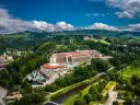 Hotel Gołębiewski w otoczeniu zielonych wzgórz i rzeki.