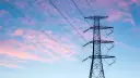 Wieża z przewodami linii energetycznej średniego napięcia na tle różowo-niebieskiego nieba.