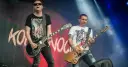 Dwóch gitarzystów na scenie, jeden w czarnej koszulce z sercem, drugi w białej z żebrami. Kocham cię jak Irlandię, grają rocka.