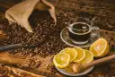 Aromatczna kawa z cytryną i miodem, otoczona ziarnami kawy wysypującymi się z worka.