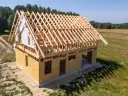 Budowa domu szkieletowego z widoczną drewnianą konstrukcją dachu i ścianami z płyt OSB.