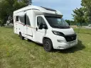 Biały kamper Burstner Lyseo Harmony Line stoi na zielonej trawie.