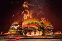 Trzy soczyste hamburgery na desce, w tle płomienie i iskry.