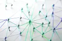 Netzwerk aus silbernen Pins und bunten Fäden auf weißem Untergrund.
