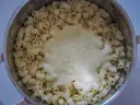Gęsty, kremowy sos serowy otula makaron w garnku, tworząc pyszny makaron mac and cheese.