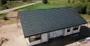Nowy dom w budowie z ciemnoszarym dachem, widok z góry.
