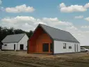 Dwa nowoczesne domy z szarym dachem i białymi ścianami, jeden z drewnianą elewacją.