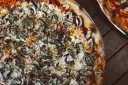 Pyszna pizza wegetariańska z pieczarkami i ciągnącym się serem, idealna na wspólny wieczór.