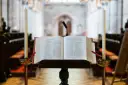 Otwarta Biblia na pulpicie, obok świece, w kościele.