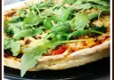Pyszna pizza z rukolą, pomidorami i serem, pachnąca ziołami. Idealna na szybki obiad.