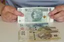Ręce trzymają stos banknotów 100 zł. Pod spodem leżą banknoty 50, 500 i 200 zł. Pytanie: co po zasiłku rehabilitacyjnym?