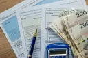 Formularze podatkowe PIT, długopis i stos banknotów 200 zł. Dokumenty sugerują rozliczenie dochodu zwolnionego od podatku.