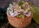 Panettone Gastronomico with sliced octopus, lettuce, and herbs on a wooden table.