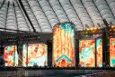 Wielkie ekrany rozświetlają stadion, tworząc barwną mozaikę. To roztanczony narodowy transmisja, gdzie sztuka i muzyka łączą się w widowiskowym spektaklu.