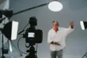 Aktor w białej koszuli gestykuluje przed kamerą. Zastanawiasz się, ile zarabia aktor w serialu?