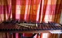 Ksylofon, instrument muzyczny na literę K, z pałeczkami, na tle czerwonej zasłony.