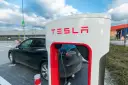 Czarna Tesla podłączona do ładowarki Supercharger.