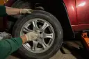 Ręce w rękawiczkach przykręcają śruby koła. Zastanawiasz się, ile kosztuje wymiana opon z wyważeniem?