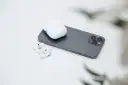 AirPods und Ladecase liegen neben einem Smartphone.