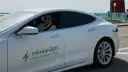 Uśmiechnięty mężczyzna w okularach przeciwsłonecznych siedzi za kierownicą białej Tesli z logo inGreen360.