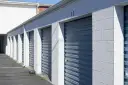 Rząd niebieskich, metalowych bram garażowych z numerami 46 i 47. Zastanawiasz się, ile kosztuje wynajem garażu?