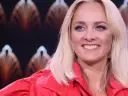 Uśmiechnięta blondynka w czerwonej marynarce, z błękitnymi oczami i delikatnym naszyjnikiem. Ola, jaka to melodia?
