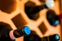 Wino w butelkach leżakuje w drewnianym stojaku. Prawidłowe przechowywanie wina w butelkach zapewnia jego jakość.