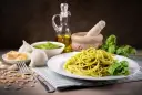 Pyszny makaron z pesto ze słoika, podany z bazylią, czosnkiem, parmezanem i orzeszkami pinii.