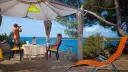 Para na plaży, relaksująca się w namiocie. Mężczyzna obserwuje morze przez lornetkę. To idealne miejsce na naturystyczny camping.
