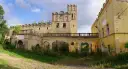 Zrujnowany zamek w Ratnie Dolnym, z charakterystyczną wieżą i arkadowym gankiem, otoczony zielenią.