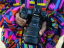 Kolorowy strój otula dłonie trzymające profesjonalny aparat cyfrowy Nikon Z6 II z obiektywem Nikkor Z 14-24mm.