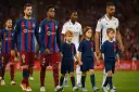 Dzieci wyprowadzają piłkarzy na boisko. Mali kibice towarzyszą zawodnikom FC Barcelony i Realu Madryt, tworząc wyjątkową atmosferę przed meczem.