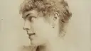 Portret Marii Wiśnowskiej z profilu, z delikatnym uśmiechem i kręconymi włosami.