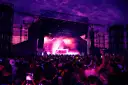 Tłum na festiwalu tańca pod fioletowym niebem. Na scenie DJ, dym i światła. To musi być świetny green festival program!